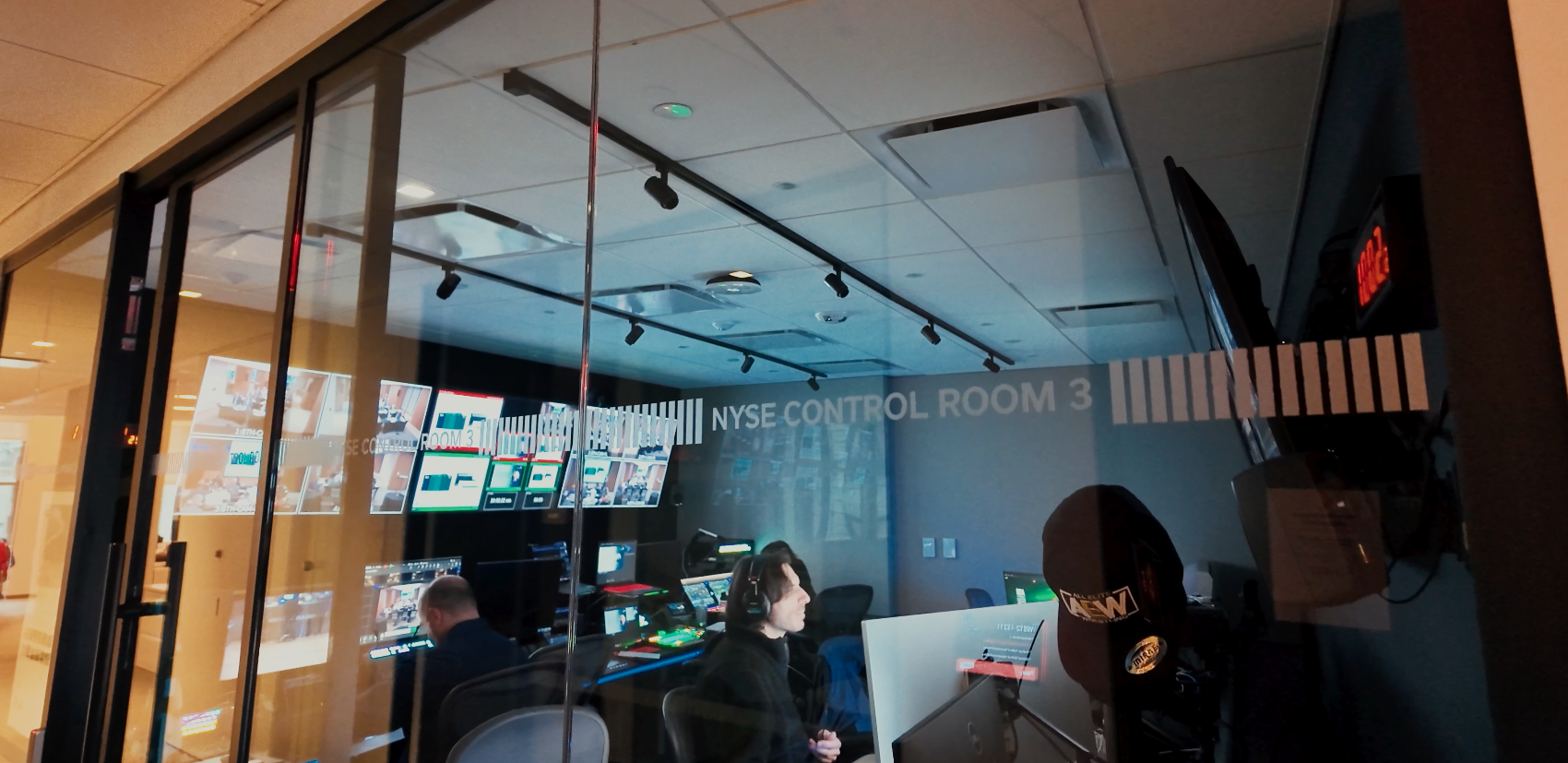 Exterior view of New York Stock Exchange Control Room 3 with production staff visible working inside.